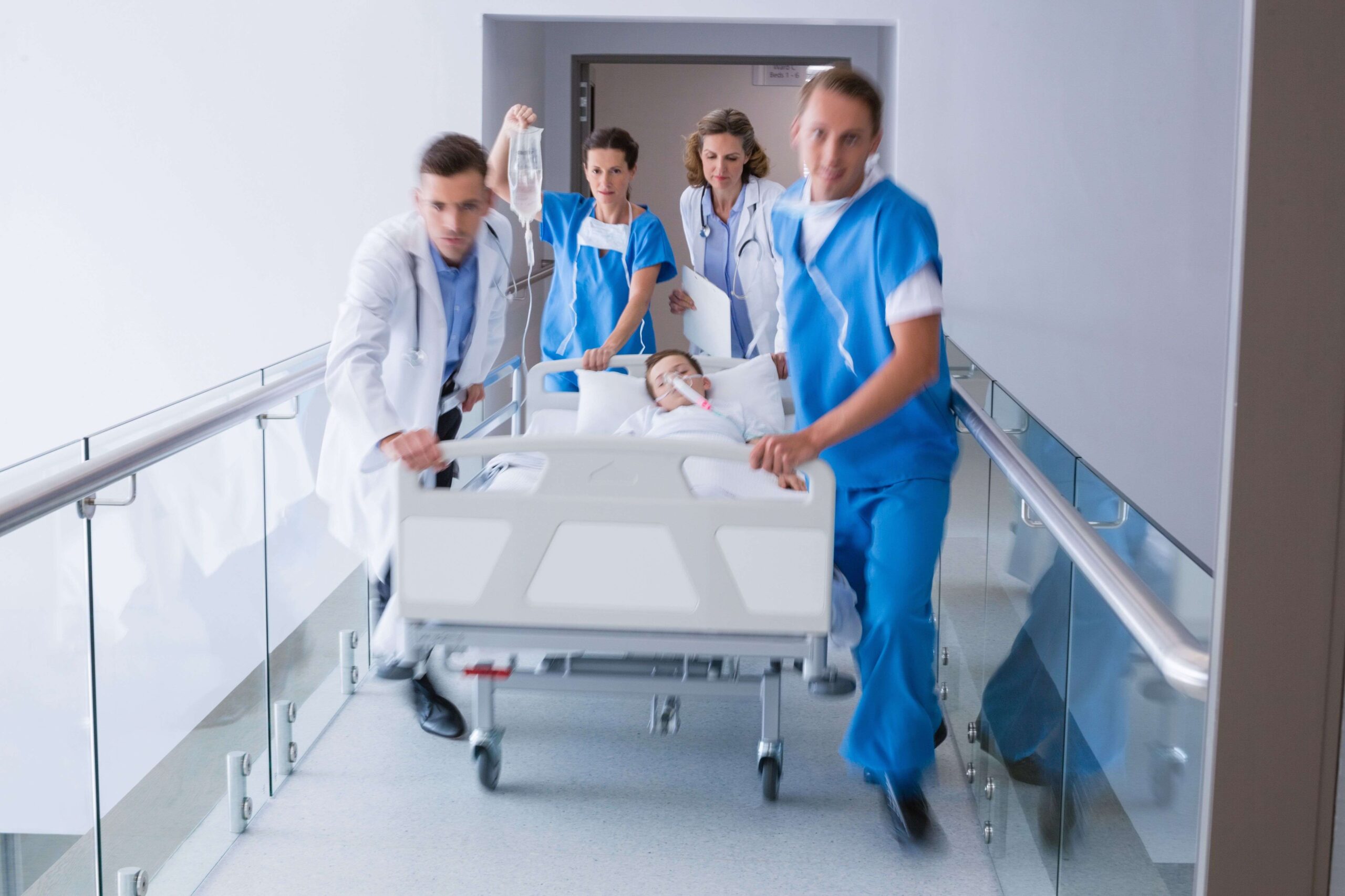 Medizinisches Team transportiert Kind im Krankenhausbett bei medizinischer Notfallsituation